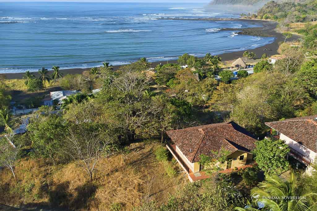 Vista aérea de propiedad cerca de la playa con olas, palmeras y construcciones cercanas