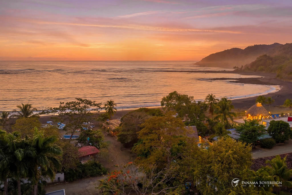 Vista aérea al atardecer de costa con iluminación cálida y casas entre vegetación