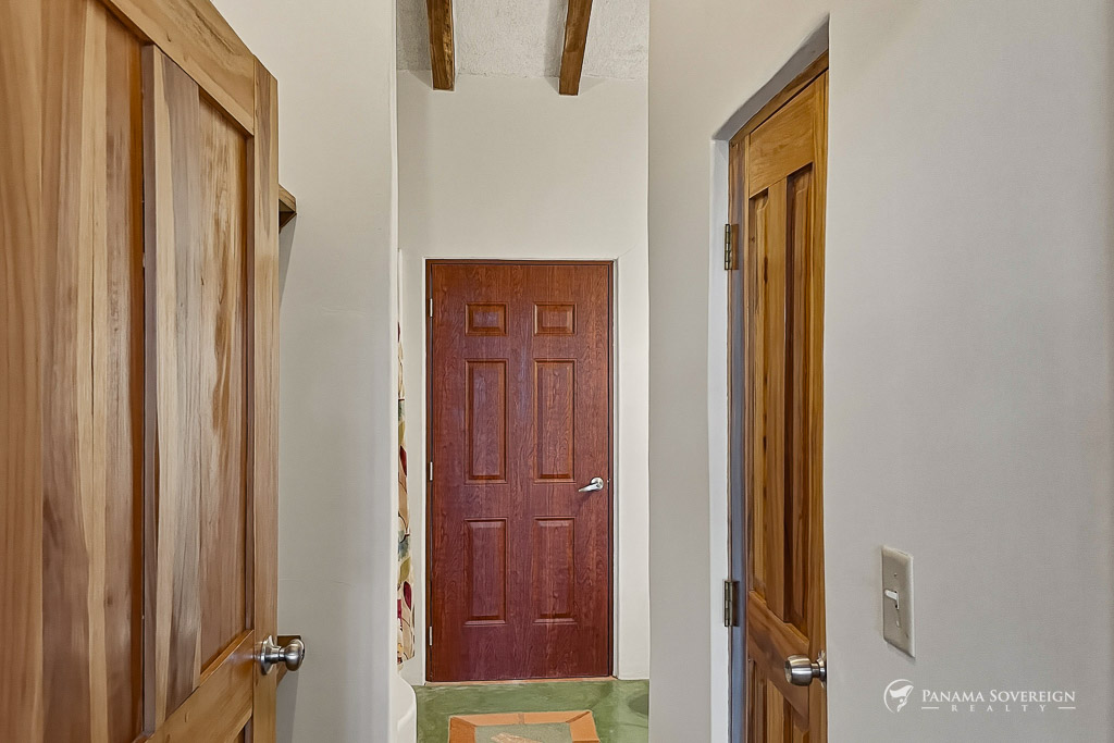 Pasillo interior con puertas de madera, techo alto con vigas expuestas y acabados rústicos