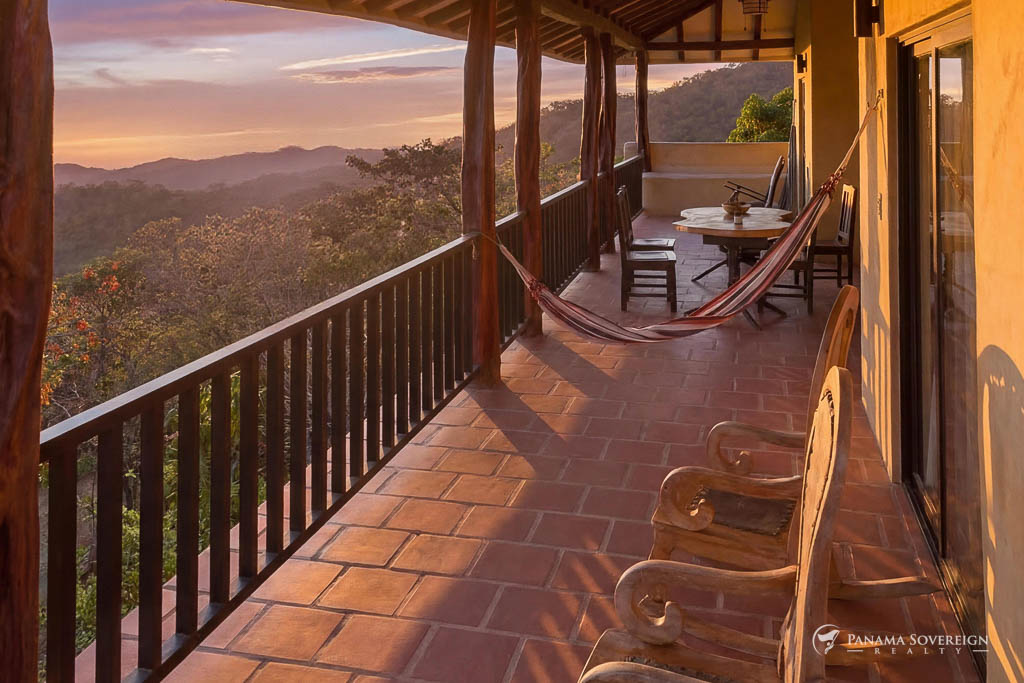 Terraza amplia con piso de terracota, hamaca, mesa exterior y vista panorámica a las montañas al atardecer