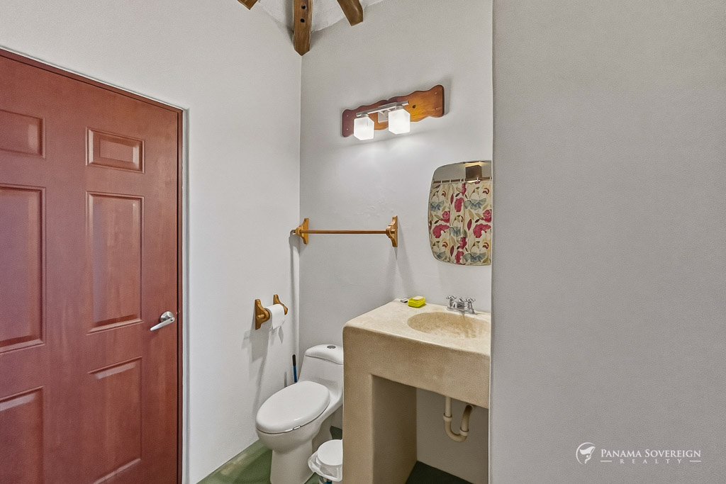 Baño de visitas con lavamanos de concreto, espejo decorativo y accesorios en madera