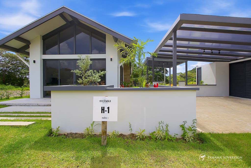 Fachada frontal moderna con diseño de techo inclinado, ventanales amplios y área de estacionamiento techado