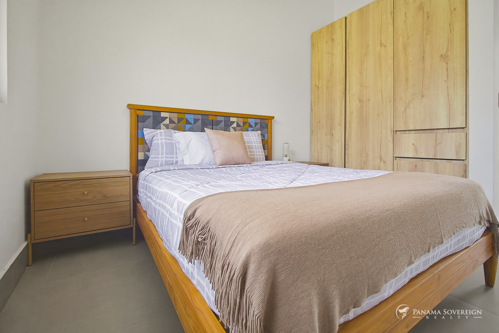 Habitación de invitados con cama de madera, cabecera con diseño, mesas de noche y estilo interior limpio y moderno