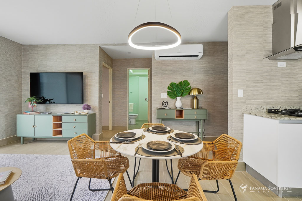 Dining area with a round table set for four, woven chairs, and a modern circular ceiling light.