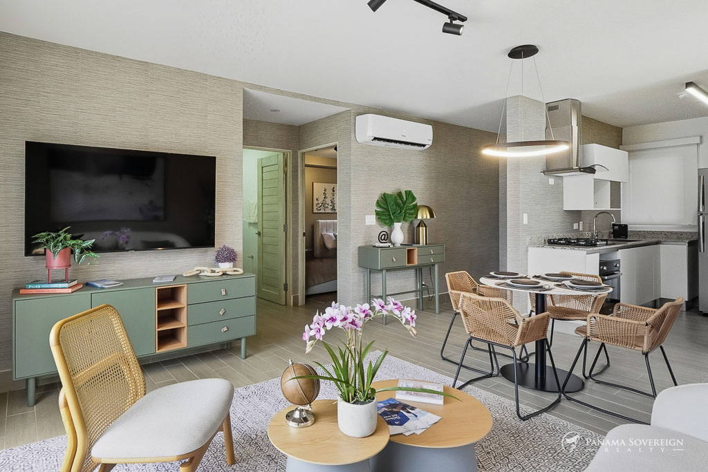 Open living and kitchen area with contemporary furnishings, wall-mounted TV, and integrated dining space.
