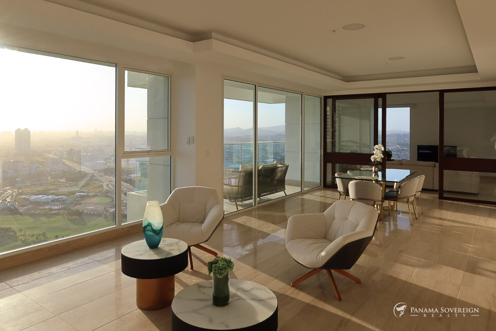 Bright living space in Santa Maria condo at sunset with stylish chairs, marble coffee tables, and expansive window views.