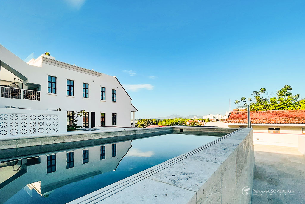 Piscina infinita en una azotea con vistas panorámicas, que ofrece un espacio sereno rodeado de arquitectura colonial restaurada.