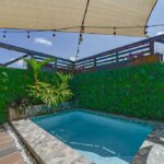 Small tiled plunge pool surrounded by lush vertical garden and shade sails.