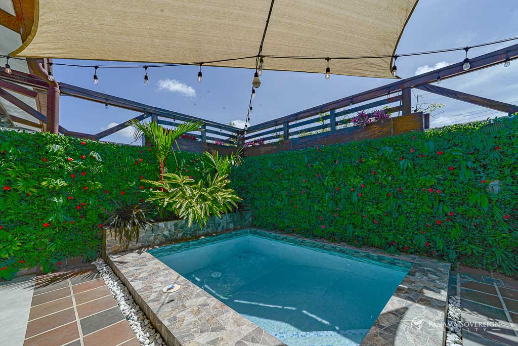 Small tiled plunge pool surrounded by lush vertical garden and shade sails.