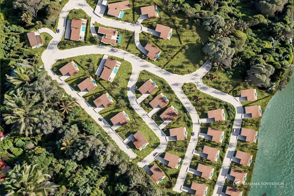 Aerial view of a community layout in Playa Venao, showcasing multiple beach homes with private pools and well-manicured paths among tropical foliage.