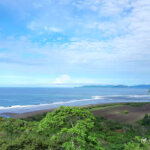 Panoramic coastline with rolling waves and clear skies, highlighting prime beachfront land suitable for residential or eco-resort use.