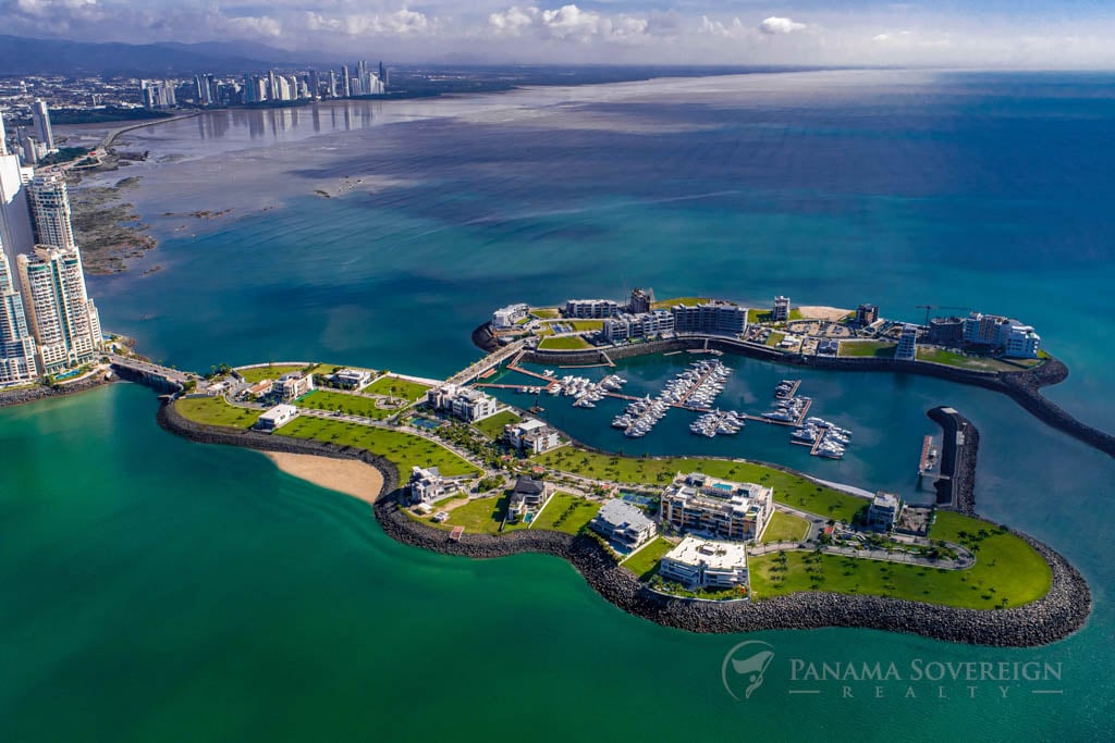 Aerial view of Ocean Reef Islands with lush green areas, modern buildings, and a marina surrounded by clear blue waters.