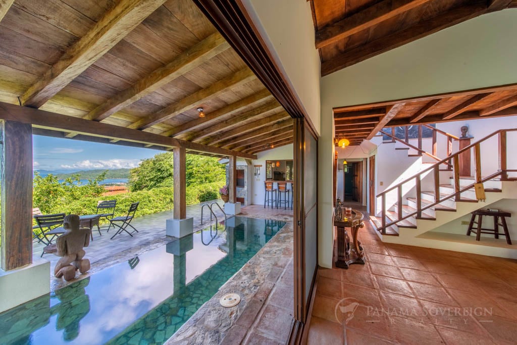 A stunning ocean view from a covered patio, framed by wooden beams, offering a peaceful and relaxing atmosphere.