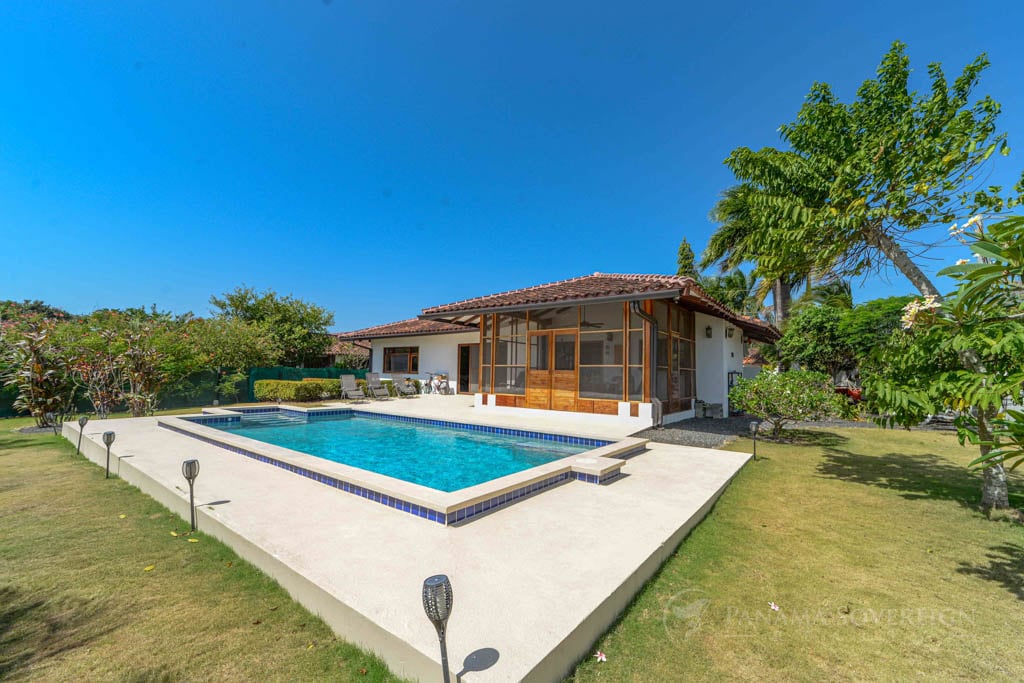 Pool with pool deck and back of house on sunny day