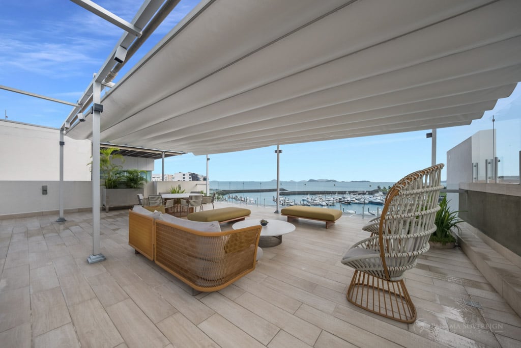 Cozy rooftop lounge area with retractable awnings, outdoor seating, and a view of the marina, offering a perfect spot for relaxation.